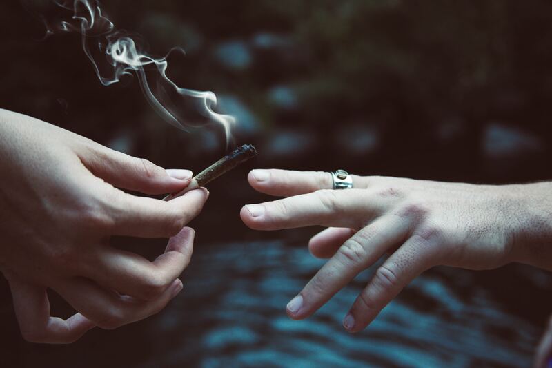 photo of a cannabis joint being passed from one hand to another