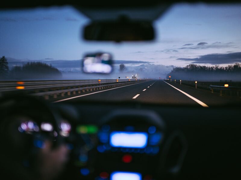 photo from inside a car looking out the windshield onto a road at night